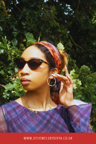 Woman wearing sunglasses and a colorful headscarf along with the amazing austrian alps inspired light weight minimalistic hoops  with a green leafy background