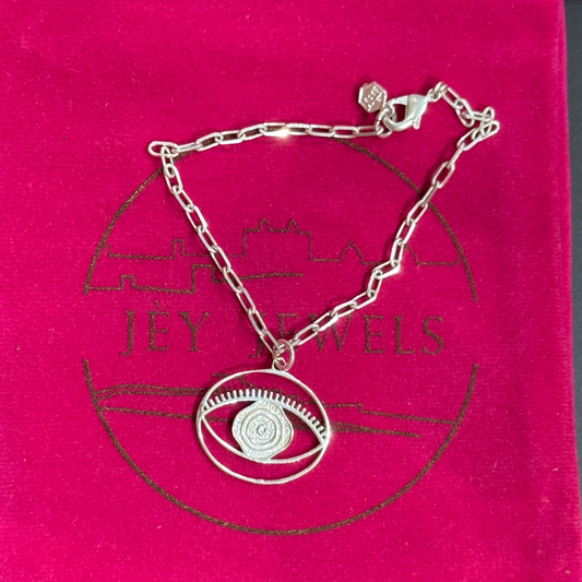 Evil Eye Dangling Bracelet Medium - Silver – handcrafted silver charm bracelet by Jey Jewels by Divya on pink background