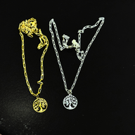 Two necklaces with tree-of-life pendants on a black background gold and silver variation, by Jéy Jewels by Divya